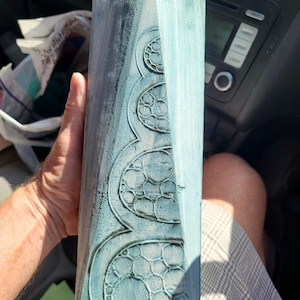 May include: A tall, rectangular, light blue and dark blue object with a weathered, distressed finish. The surface features a series of embossed, circular, interconnected patterns that resemble a honeycomb or bubble-like structure.