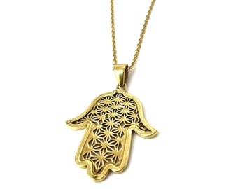 May include: A gold chain necklace with a hamsa hand pendant. The pendant is intricately designed with a geometric pattern.