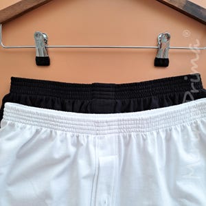 May include: Two pairs of underwear, one black and one white, hanging on a clothes hanger.