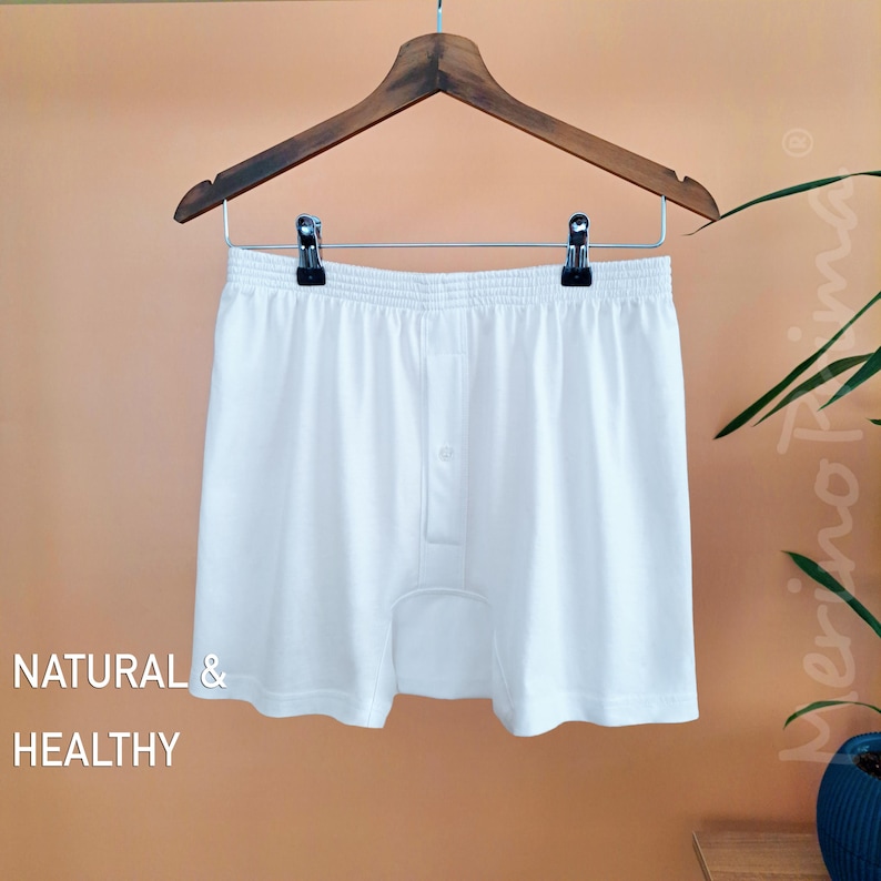 May include: White boxer shorts with a button fly. The shorts are hanging on a wooden hanger. The text "NATURAL & HEALTHY" is visible in the lower left corner of the image.