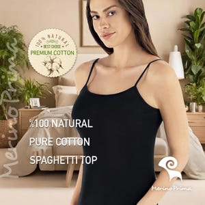 May include: A black spaghetti strap tank top made of 100% natural pure cotton. The tank top is shown on a model with the text "100% NATURAL PURE COTTON SPAGHETTI TOP" printed on the front.