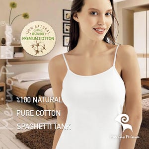 Peut inclure: Un débardeur blanc à bretelles spaghetti en pur coton 100% naturel. Le débardeur est présenté sur un mannequin avec le texte "100% NATURAL PURE COTTON SPAGHETTI TANK" et le logo "Merino Prima" en bas.
