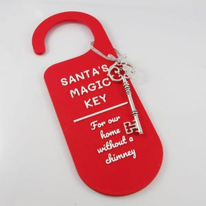 May include: Red door hanger with a silver key attached. The hanger says "Santa's Magic Key" and "For our home without a chimney".