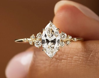 May include: A gold engagement ring with a large marquise-shaped diamond surrounded by smaller diamonds. The ring is set on a delicate band.