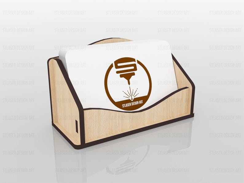 Puede incluir: Un tarjetero de madera de color claro con bordes de color marr&oacute;n oscuro, que contiene una pila de tarjetas de visita blancas. Cada tarjeta presenta un logotipo circular marr&oacute;n de una herramienta de corte l&aacute;ser con el texto STLASER DESIGN ART.
