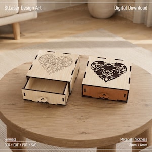May include: Two light-colored wooden boxes with sliding drawers, each featuring a laser-cut heart design on the lid. One box displays an intricate floral heart outline, while the other features a solid dark heart pattern with cutouts.