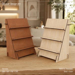 Op de afbeelding: Twee houten displaystandaards met elk drie niveaus, één in een donkerbruine afwerking en één in een lichte natuurlijke houtafwerking. De tekst StLaser Design Art, Digital Download, Formats CDR DXF PDF SVG en Material Thickness 3mm 4mm is zichtbaar.
