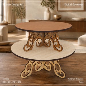Puede incluir: Un expositor circular de dos niveles con una bandeja superior marrón oscuro y una inferior beige claro. Ambos niveles se apoyan en bases de corte láser con intrincados diseños de volutas. Texto visible: S Laser Design Art.