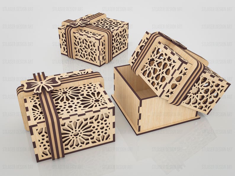 May include: Three square wooden gift boxes featuring intricate laser-cut geometric patterns on the lids and sides. Each box includes a decorative wooden ribbon and bow detail on top. One box is shown open with the lid resting beside the base.