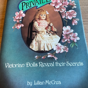 Puede incluir: Un libro titulado "Private Lives: Victorian Dolls Reveal their Secrets" de Lillian McCrea. La portada presenta una muñeca vintage con un vestido blanco que sostiene una muñeca más pequeña. El fondo es de color azul verdoso con flores rosas.