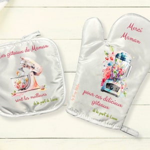 May include: A set of two white oven mitts with floral designs and text in French. The mitts feature a vintage-style kitchen appliance, a stand mixer and a blender, with the text "Les gâteaux de Maman sont les meilleurs de la part de Lu" and "Merci Maman pour ces délicieux gâteaux de la part de Lu".