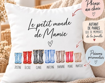 May include: A white square throw pillow featuring the black text Le petit monde de Mamie, a small heart icon, and a row of seven pairs of illustrated rain boots in various colors and patterns, each labeled with names: Justine, Eloise, Claire, Antoine, Barnabe, Pierre, and Anatole.