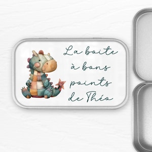 Peut inclure: Une boîte en métal argentée avec un dragon de dessin animé coloré sur le couvercle. Le texte sur le couvercle est "La boîte à bons points de Théo".