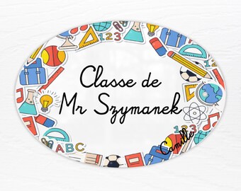 May include: White oval classroom door sign with a colorful border of school supplies and the text "Classe de Mr Szymanek".