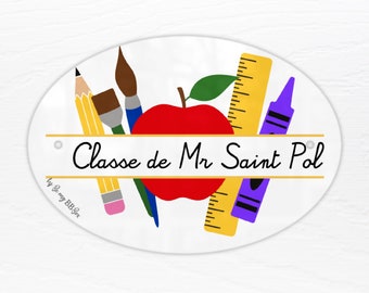 May include: A white oval sign with a gold border and the text "Classe de Mr Saint Pol". The sign features a red apple, a yellow pencil, a blue paintbrush, a yellow ruler, and a purple crayon.
