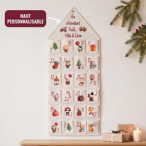 Peut inclure: Un calendrier de l'Avent en tissu en forme de maison avec vingt-quatre poches numérotées. Le haut porte le texte En attendant Noël et les prénoms Mila & Léon. Chaque poche présente une illustration de Noël unique, incluant animaux et cadeaux.