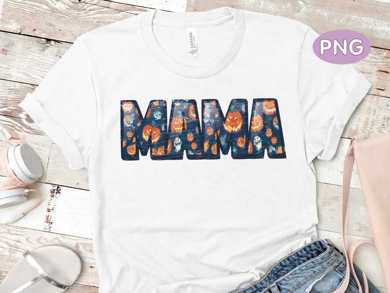 May include: White t-shirt with a blue "MAMA" graphic. The letters are filled with a pattern of orange pumpkins and ghosts.