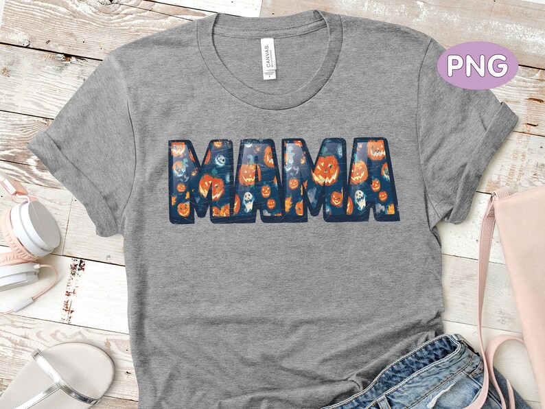 May include: A gray t-shirt with a graphic of the word "MAMA" made up of images of pumpkins and ghosts. The shirt has a distressed look.