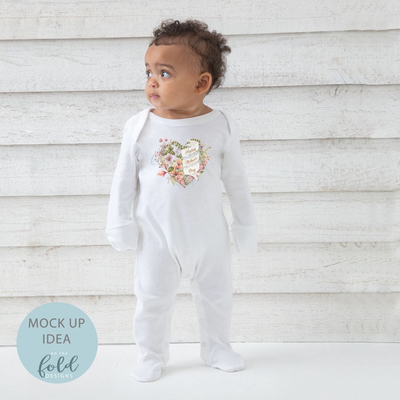 May include: White baby onesie with a heart-shaped floral design and the text "Happy Mother's Day".