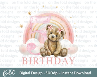 May include: A pink and gold rainbow with a teddy bear sitting in front of it. The rainbow has a pink, gold, and white design. The teddy bear is brown with a pink bow. The text "BIRTHDAY" is written in pink letters below the rainbow.