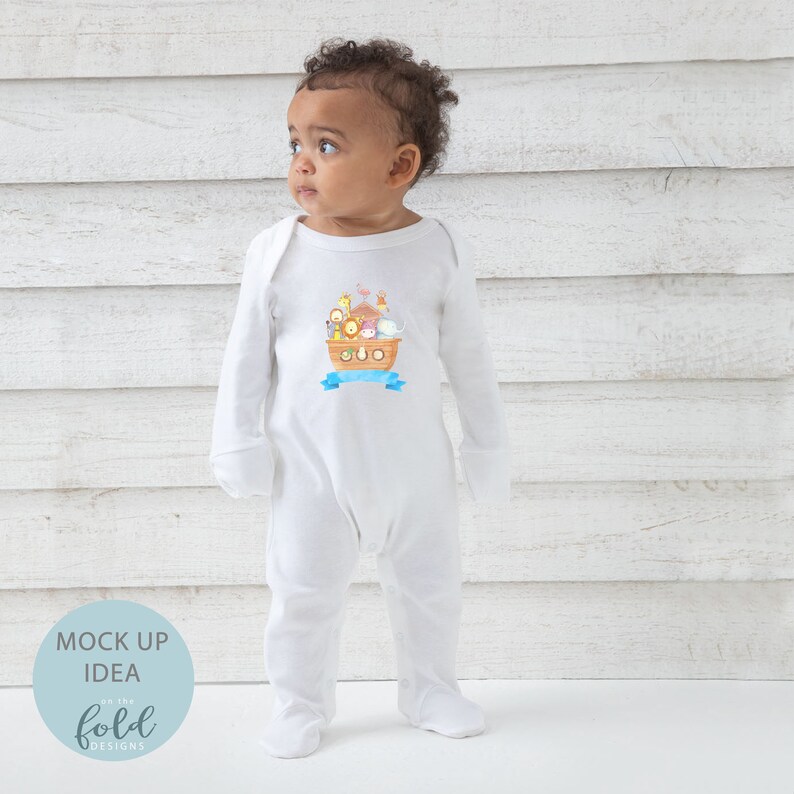 May include: White baby footed onesie with a colorful illustration of animals on a boat, including a giraffe, lion, and elephant. The design includes a blue banner. The onesie has long sleeves and foot coverings.