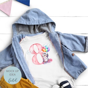 May include: A white t-shirt with a pink number eight and a penguin holding colorful balloons. The text "on the fold designs" is printed on the shirt.