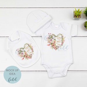 May include: A white baby bodysuit, bib, and hat with a floral heart design and the text "Happy Mother's Day".
