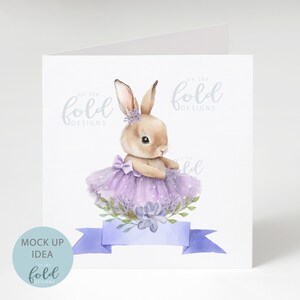 Peut inclure: Une illustration aquarelle d'un lapin brun portant un tutu violet et une couronne de fleurs. Le lapin est entour&eacute; de fleurs violettes et de feuilles vertes. Le texte "on the fold designs" est &eacute;crit en bleu clair en haut de la carte.