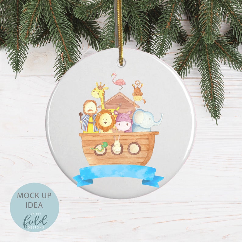 May include: A round white Christmas ornament with a watercolor illustration of Noah's Ark. The ark is filled with pairs of animals, including a giraffe, lion, hippo, and elephant. A blue ribbon is at the bottom. The ornament is hanging from a gold string.