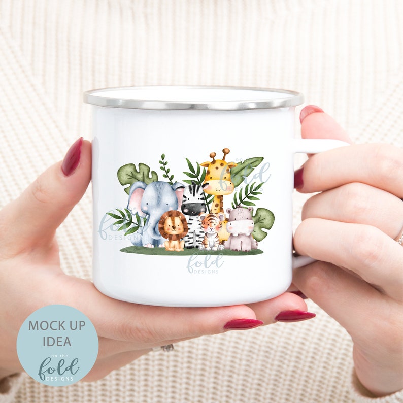 May include: White enamel mug with a colorful illustration of a group of jungle animals including a giraffe, zebra, lion, elephant, and hippopotamus. The animals are surrounded by green leaves. The mug has a silver rim and handle.
