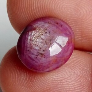 Peut inclure: Une pierre précieuse ronde de couleur rose avec un motif en forme d'étoile. La pierre précieuse est taillée et polie, et elle a une surface brillante et réfléchissante.