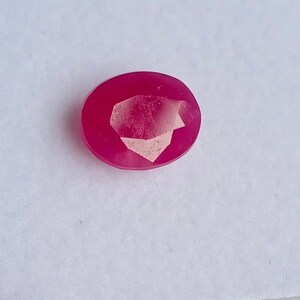 May include: A pink oval-shaped gemstone with a faceted cut.
