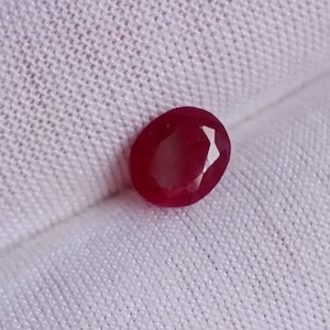 Może przedstawiać: Owalny kamień szlachetny w kolorze głębokiej czerwieni o szlifie fasetowym.
