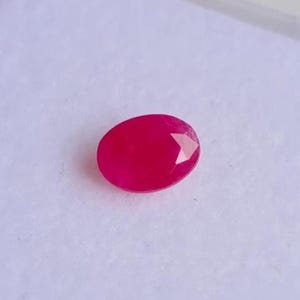 May include: A vibrant pink oval-shaped gemstone with a faceted cut.
