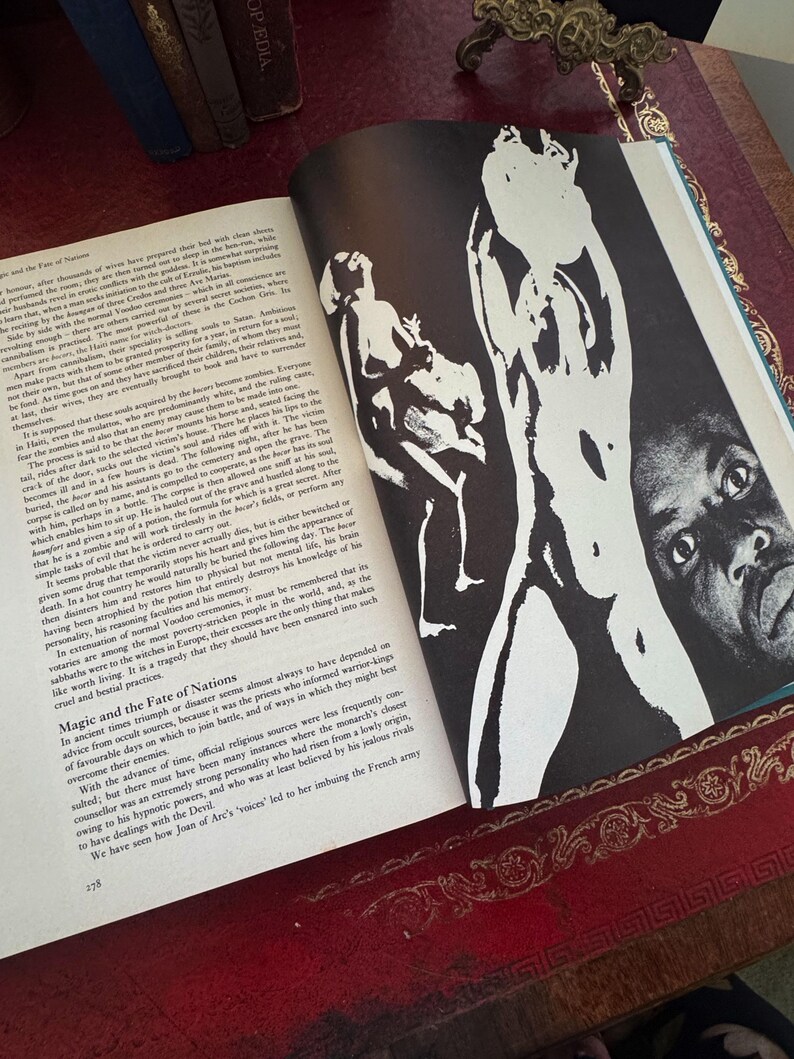 May include: Open book with black and white illustrations of figures and text. The book is open to a page with a large illustration of a figure with a dark background. The text is in English.