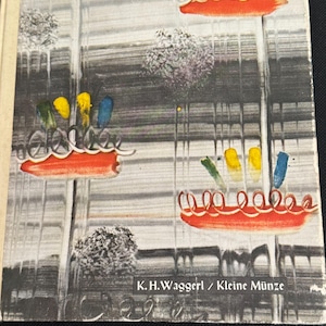 May include: A vintage book cover with an abstract painting. The artwork features a gray and white background with red, yellow, blue, and green accents. The text "K.H.Waggerl / Kleine Münze" is printed on the bottom.