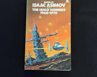 May include: A vintage paperback book titled "The Hugo Winners 1968-1970" edited by Isaac Asimov. The cover features a science fiction illustration of a futuristic city and spacecraft against an orange and yellow starry sky.