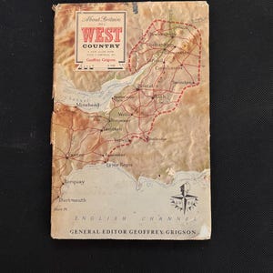 May include: A vintage travel guide titled "About Britain: West Country" with a map of the region. The cover is aged with a faded color palette of beige, brown, and red. The guide includes a compass rose and the English Channel.