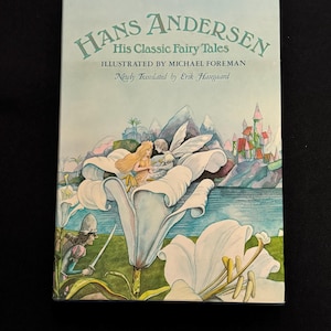 Peut inclure: Un livre de contes intitulé "Hans Andersen His Classic Fairy Tales", illustré par Michael Foreman. La couverture présente une illustration à l'aquarelle d'une scène de conte de fées avec un château, de l'eau et des fleurs blanches.