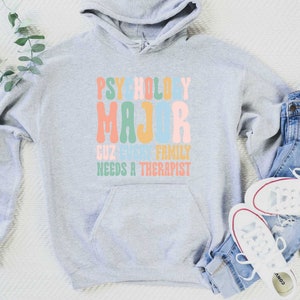May include: Grey hooded sweatshirt with the text "Psychology Major Cuz Every Family Needs A Therapist" in colourful retro font.