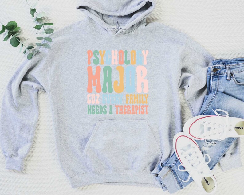 May include: Grey hooded sweatshirt with the text "Psychology Major Cuz Every Family Needs A Therapist" in colourful retro font.