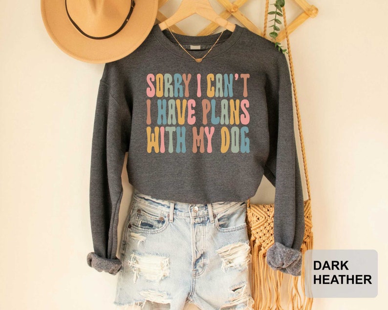 May include: Dark heather grey sweatshirt with the text "Sorry I can't I have plans with my dog" in rainbow colors.