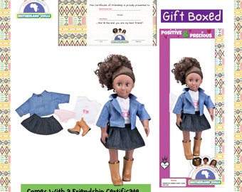 Puede incluir: Una muñeca de piel morena con cabello castaño rizado que lleva una chaqueta vaquera azul, una camisa blanca con un diseño de mariposa rosa, una falda vaquera azul y botas marrones. La muñeca sostiene un certificado de amistad. La muñeca viene en una caja de regalo con las palabras "Gift Boxed" y "Positive & Precious" impresas en ella.