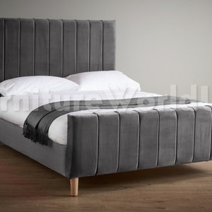 May include: A grey upholstered bed frame with a tall headboard featuring vertical channel tufting. The bed frame has a simple design with wooden legs.