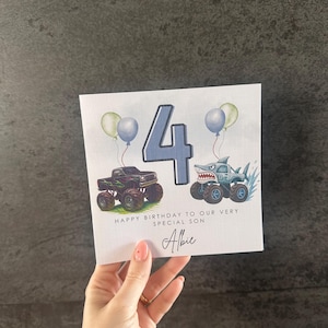 May include: A birthday card with a blue number 4, two monster trucks, and balloons. The card says "Happy Birthday to our very special son" and is personalized with the name "Albie".