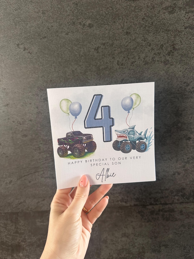May include: A birthday card with a blue number 4, two monster trucks, and balloons. The card says "Happy Birthday to our very special son" and is personalized with the name "Albie".