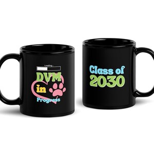 May include: Two black coffee mugs with a white loading bar and text. One mug says "DVM in Progress" with a pink heart and paw print. The other mug says "Class of 2030".