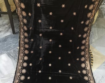 May include: A black velvet shawl with gold embroidery. The shawl features a floral design with a border of gold sequins.