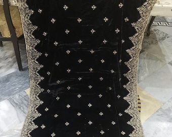 May include: A black velvet shawl with detailed gold embroidery along the borders and across the fabric. The shawl is rectangular and is displayed, highlighting the ornate design and luxurious texture of the material.