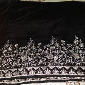 May include: Black velvet shawl with silver embroidery of floral designs. The embroidery is along the bottom edge of the shawl.